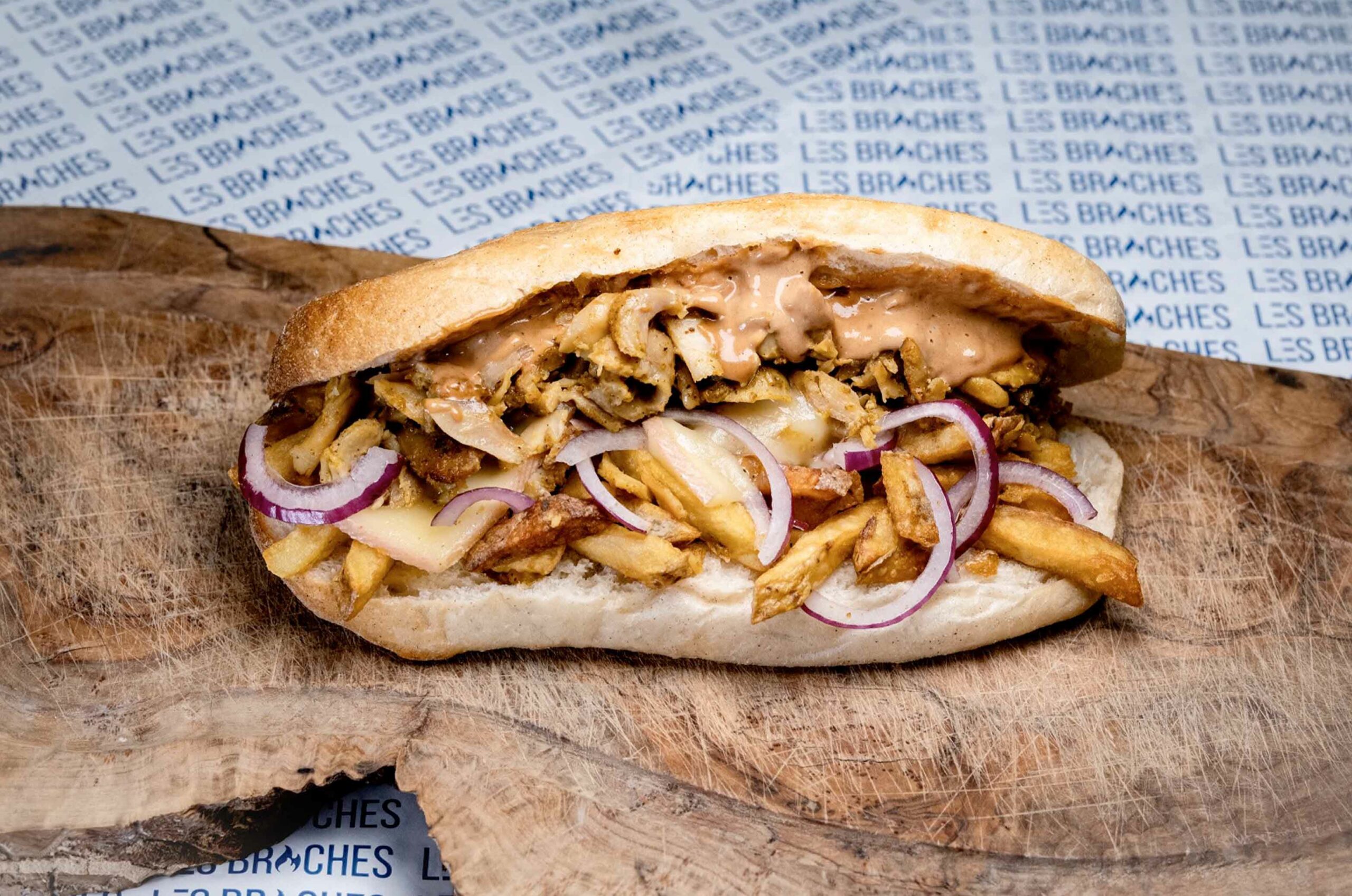 picture of an kebab on a piece of wood above some paper with the name brand "Les Broches"