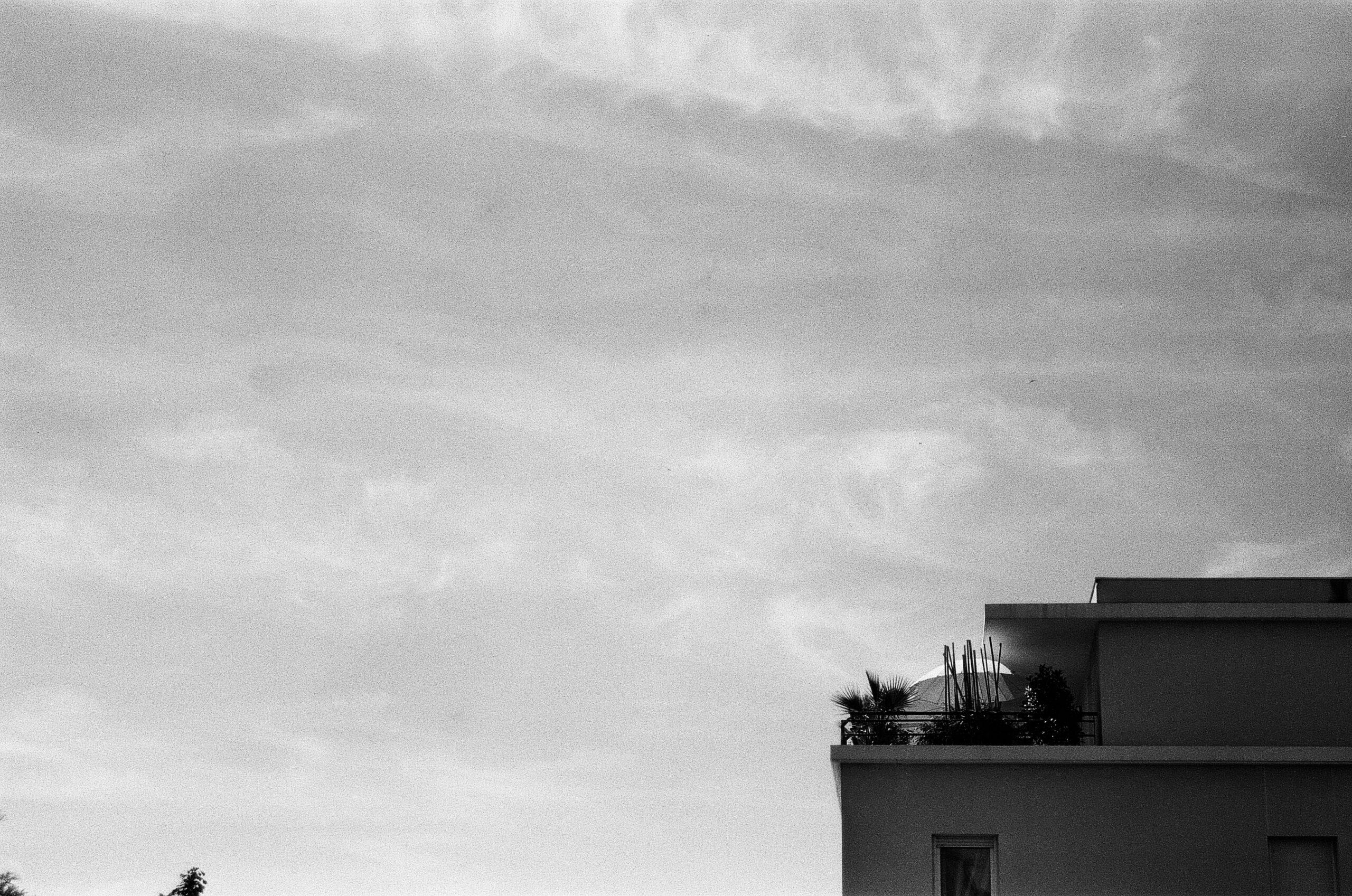 Black & White picture with a balcony at the right hand orner bottom and the rest is the sky. The can see an umbrella on the balcony