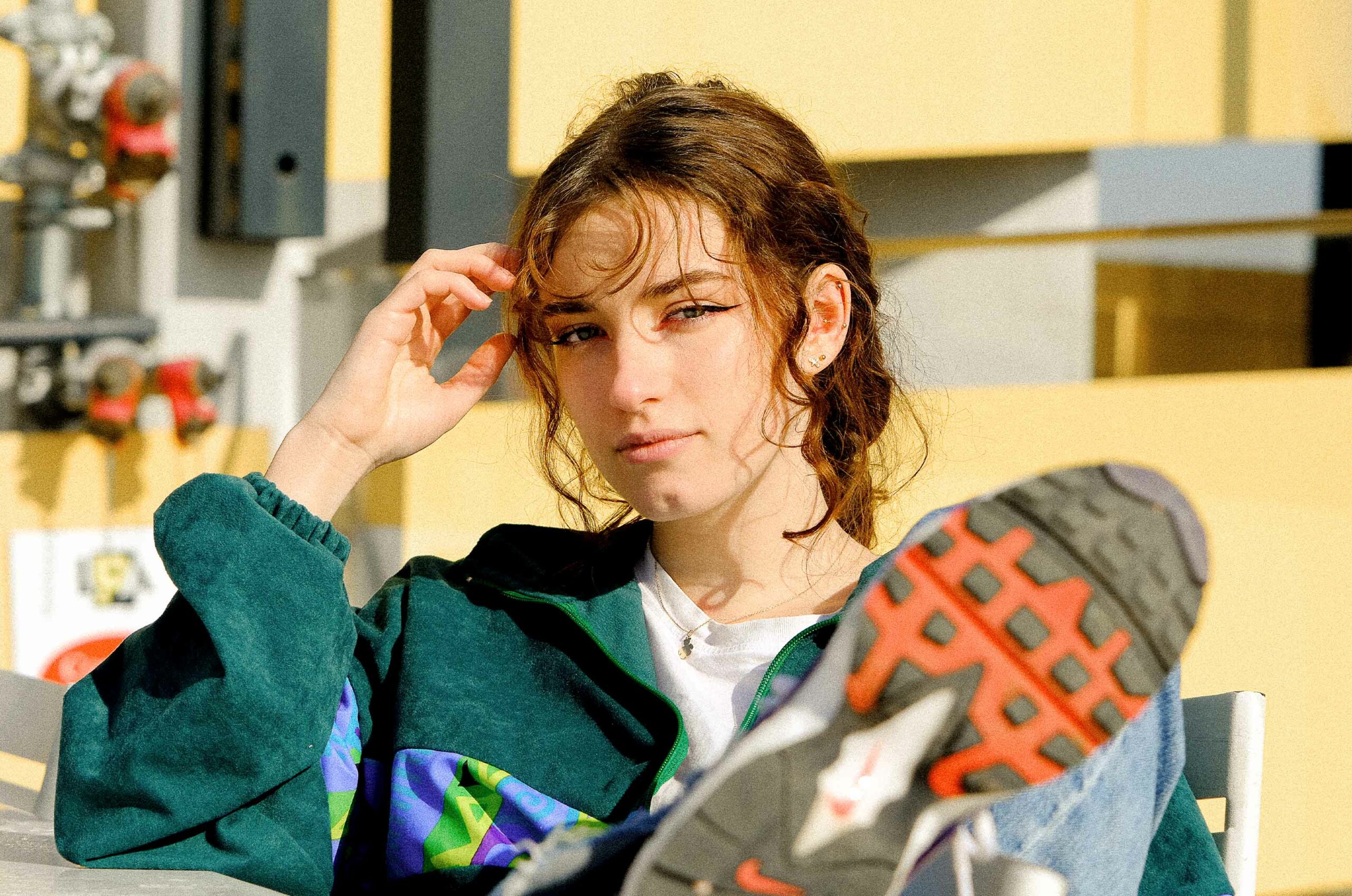 Portrait of a white woman with brown hair, a green jacquet, who look to the cam. We can see in the first plan her Nike red shoes
Take in Lyon, France